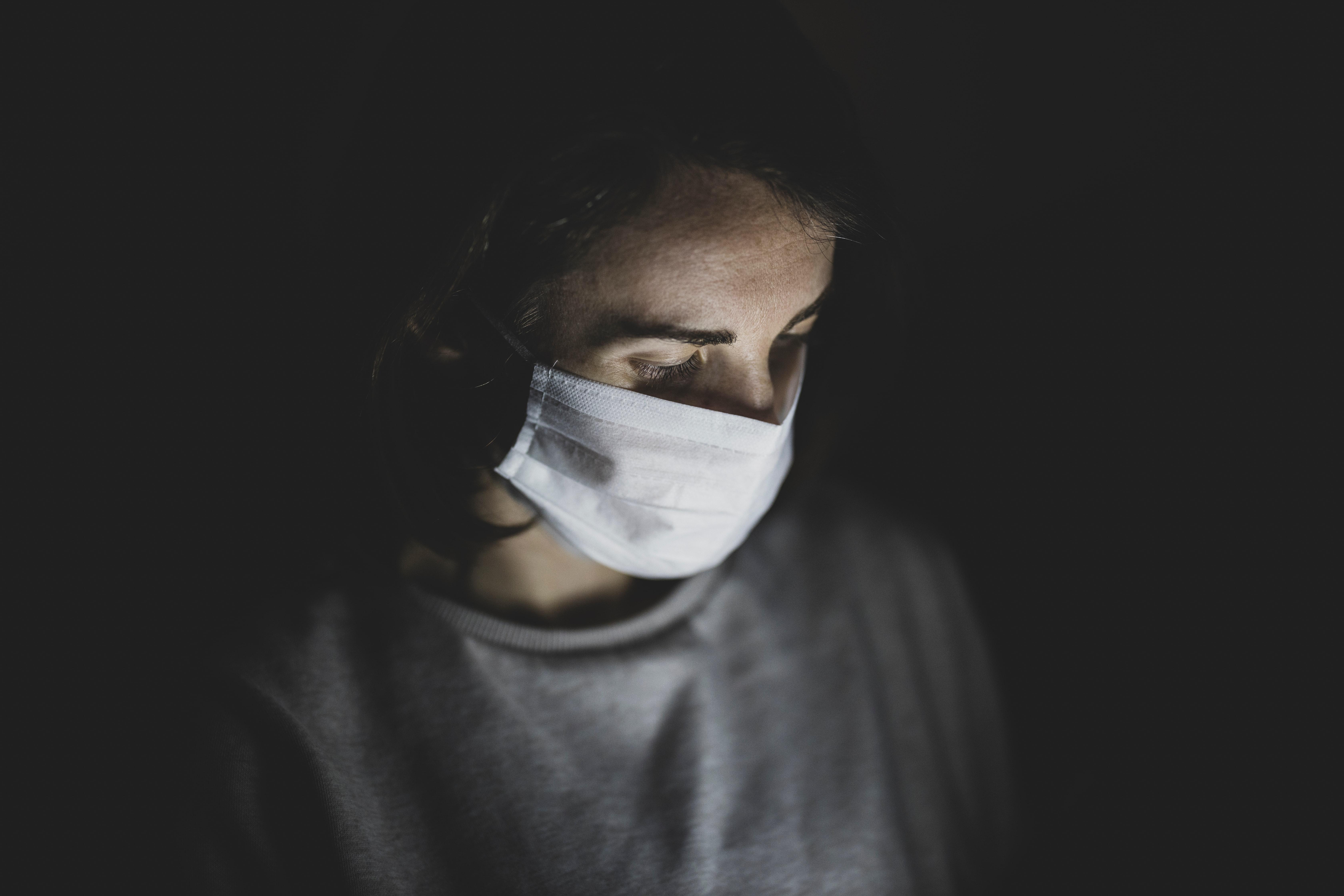 Woman in mask in dark room.